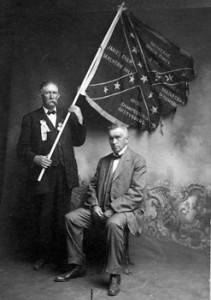 Prof. William Irvin Gibson (seated) served with the 2nd Regiment, Mississippi Infantry during the Civil War. Gibson served as president of Burleson College in Greenville.  Later Gibson taught Greek and Latin at the school.  This photograph may have been taken during the Confederate Veterans Reunion in Greenville.  The man holding the flag is not identified.